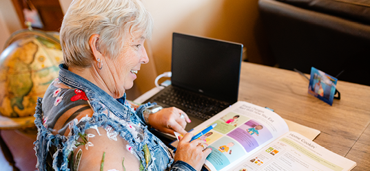 elderly woman on laptop and reading a book