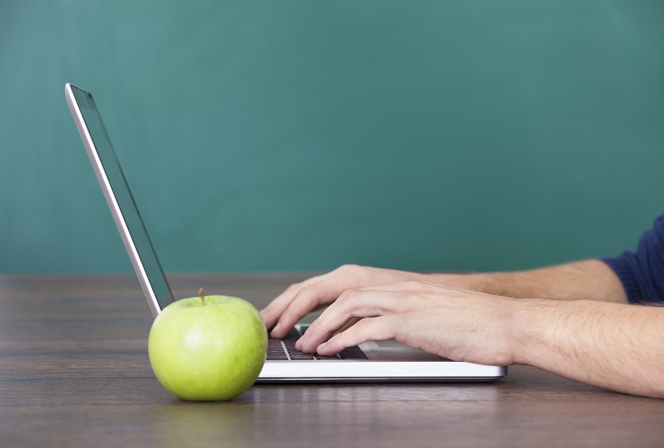 Person Using Laptop Besides Green Apple
