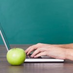 Person Using Laptop Besides Green Apple