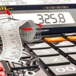 Shopping cart on calculator and receipt. Home budget or consumer