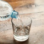 blue water bottle poured into a clear glass