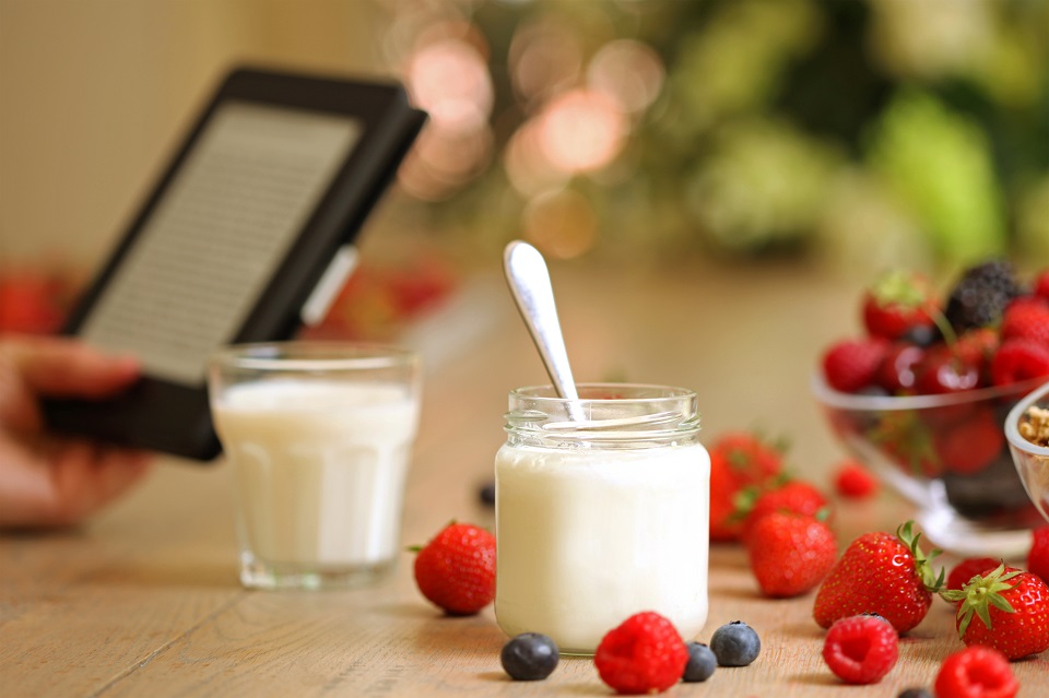 Person Reading e-book over Healthy Breakfast