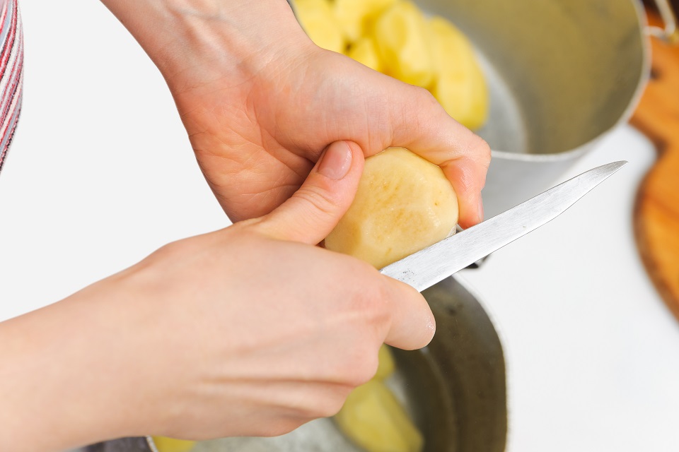 Woman cutting to peel potatoes. Kitchen working. Prepare food