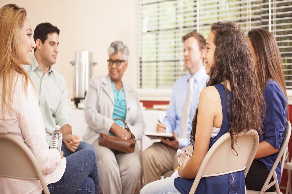 Multi-ethnic group of people in counseling session with therapist.