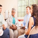 Multi-ethnic group of people in counseling session with therapist.