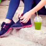 Green detox smoothie cup and woman lacing running shoes