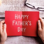 Fathers day composition. Hands of dad holding greeting card