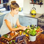 Young woman picking mint leaves at kitchen island