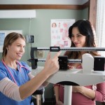 Nurse checking weight of pregnant woman