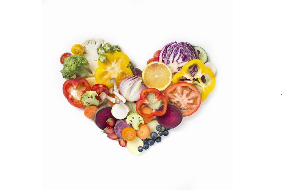Flat lay conceptual vegan food in heart shape on white background.