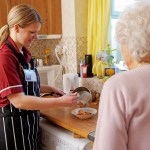 young Nurse cooking for senior woman in her kitchen