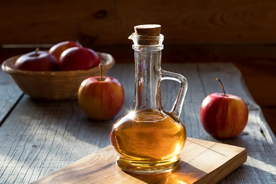 A bottle of apple cider vinegar with apples