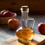 A bottle of apple cider vinegar with apples