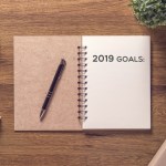 2019 goals list in notebook with gift box new year on wooden table background.