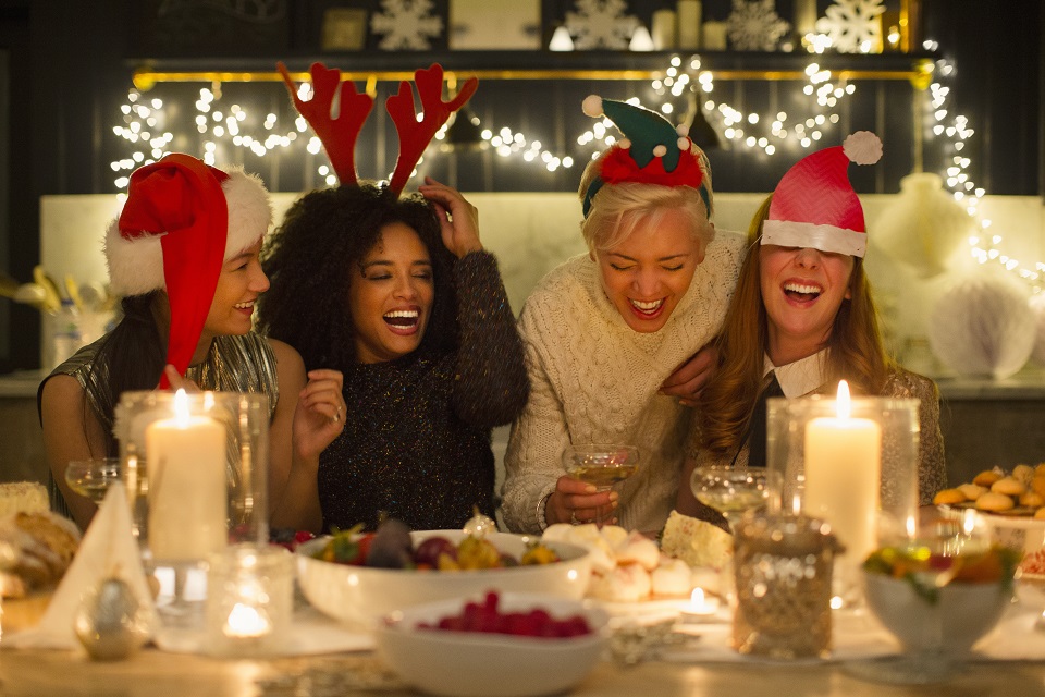 Laughing friends enjoying candlelight Christmas dinner