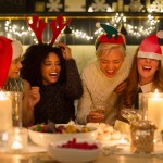Laughing friends enjoying candlelight Christmas dinner