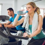 Young sporty woman drinking water during exercising training.