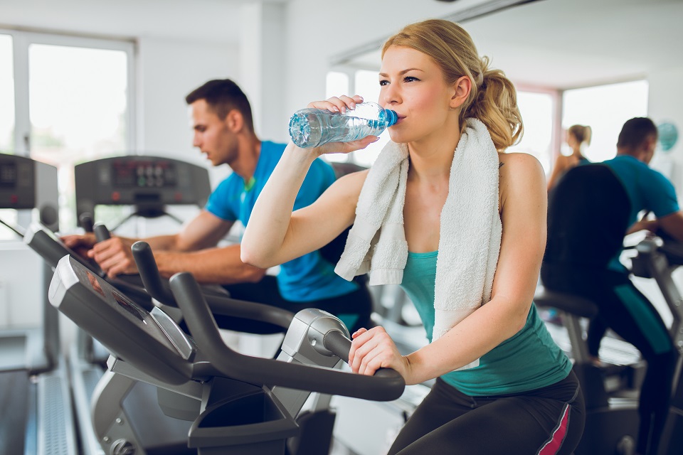 Young sporty woman drinking water during exercising training.