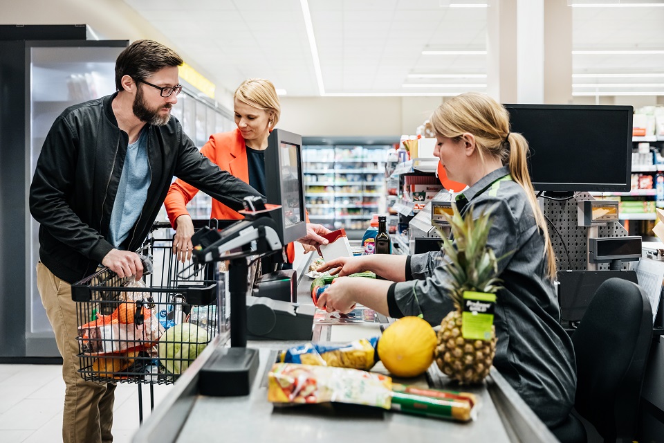 Mature Couple Putting Groceries On Conveyor At Checkout