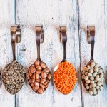 Row of spoons with different dried pulses