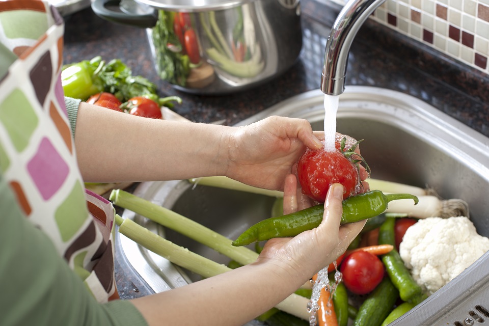 hands shown washing fresh produce under running water