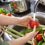 hands shown washing fresh produce under running water