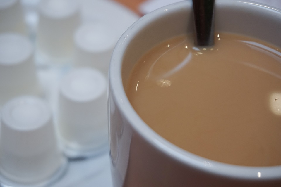 Cup of coffee with cream and individual creamers in background