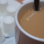 Cup of coffee with cream and individual creamers in background
