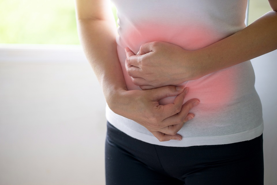 Woman holding her stomach with two hands.