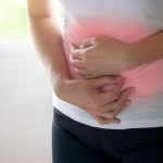 Woman holding her stomach with two hands.