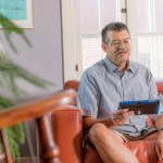 Home dialysis patient setting on a couch while using monitoring device.
