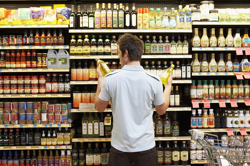 Man in grocery store looking at bottles of cooking oil