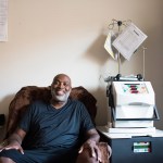 A man setting in a chair beside home hemodialysis machine.