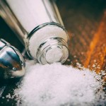 Close-up shot of a salt shaker on wooden table.