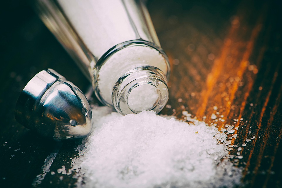 Close-up shot of a salt shaker on wooden table.