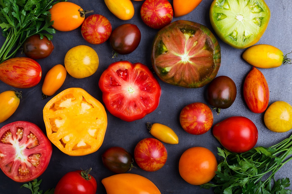 Colorful ripe heirloom tomatoes over gray table viewed from above
