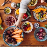 Cropped image of woman picking up vegetables at wooden table
