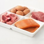 Close up of sectioned plate with eggs, pork, salmon and steak