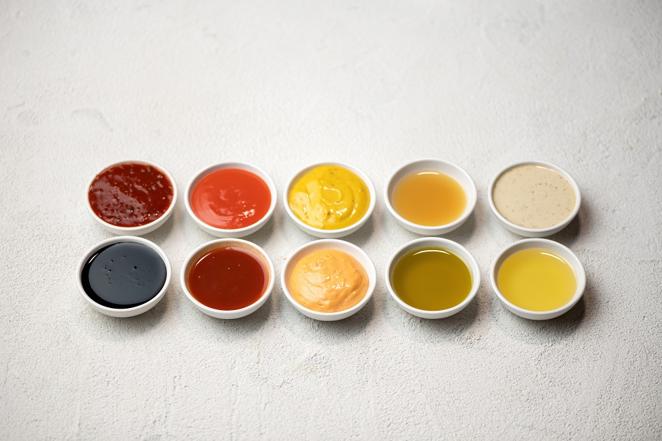 Big Set of colored sauces in Crockery. Different sauces, mayonnaise, mustard, soy sauce, oil and ketchup on white background. Top side view. Tasty food. Kitchen utensils