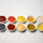 Big Set of colored sauces in Crockery. Different sauces, mayonnaise, mustard, soy sauce, oil and ketchup on white background. Top side view. Tasty food. Kitchen utensils