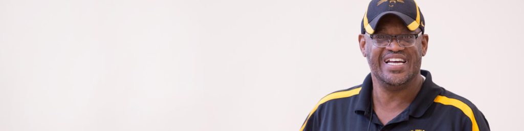 Man smiling with a black and yellow shirt and hat on