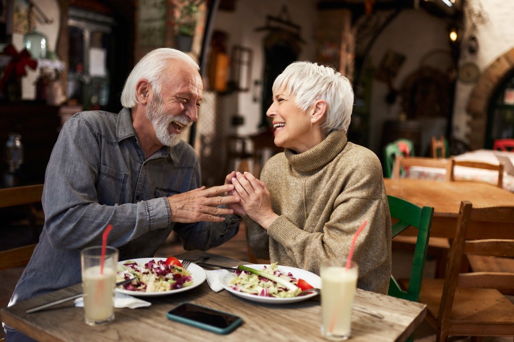 Cheerful mature couple talking during lunch at restaurant.